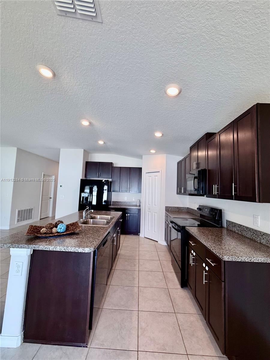 39889 Harmon Grove Court Zephyrhills, FL 33540 - Photo 8 of 55 a kitchen with stainless steel appliances granite countertop a stove a sink a refrigerator and a wooden cabinets