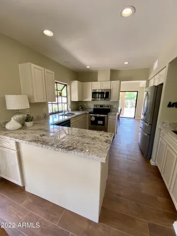 a kitchen with kitchen island granite countertop a sink counter top space appliances and cabinets