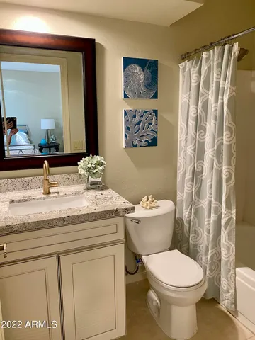 a bathroom with a granite countertop toilet sink and mirror