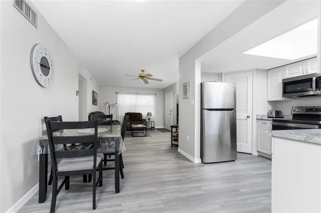 a kitchen with a refrigerator a dining table and chairs