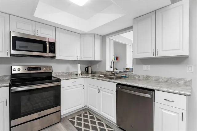 a kitchen with stainless steel appliances granite countertop grey cabinets a stove a sink and dishwasher