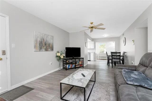 a living room with furniture and a flat screen tv with kitchen view