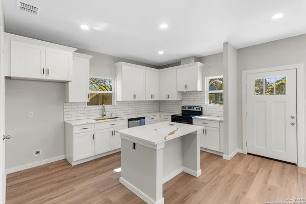 a kitchen with cabinets appliances wooden floor and a window