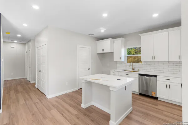 a kitchen with a sink wooden floor and white cabinets