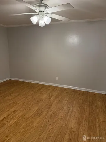 an empty room with wooden floor and fan