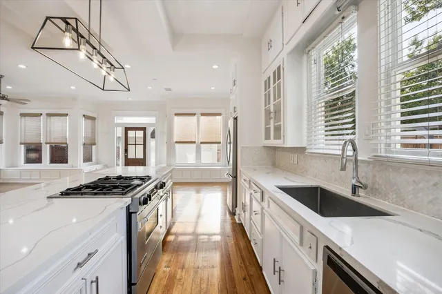 a kitchen with stainless steel appliances a sink a stove cabinets and a window