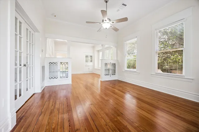 a view of an empty room with wooden floor and a window
