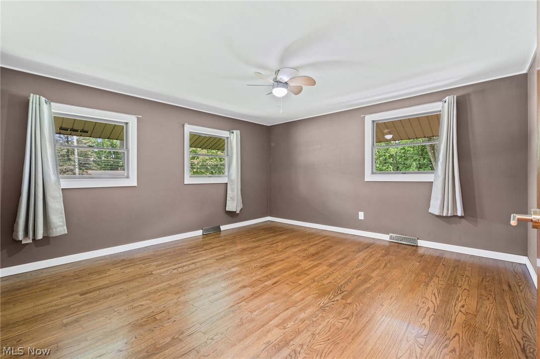 17583 Shurmer Road Strongsville, OH 44136 - Photo 27 of 50 Room featuring wood-finish flooring, a ceiling fan with integrated lighting, and multiple windows with white trim