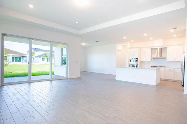 a view of kitchen with kitchen island a sink wooden floor and a refrigerator in it