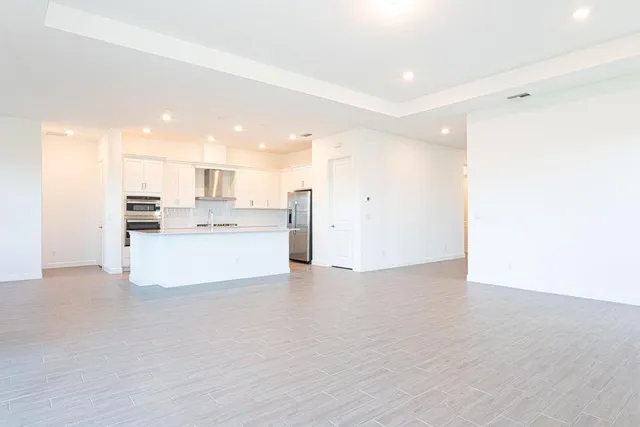 a view of a kitchen with kitchen island a sink wooden floor and a large window
