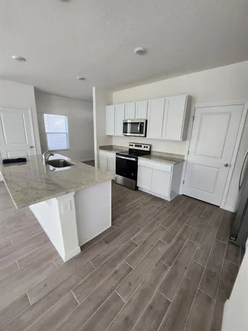 a kitchen with a sink cabinets and wooden floor