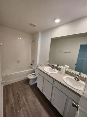 a bathroom with a granite countertop sink toilet a large mirror and shower