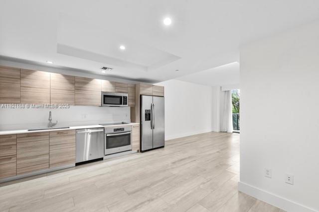 121 Northeast 34th Street, Unit L303 Miami, FL 33137 - Photo 4 of 36 a large kitchen with stainless steel appliances granite countertop a stove and a sink