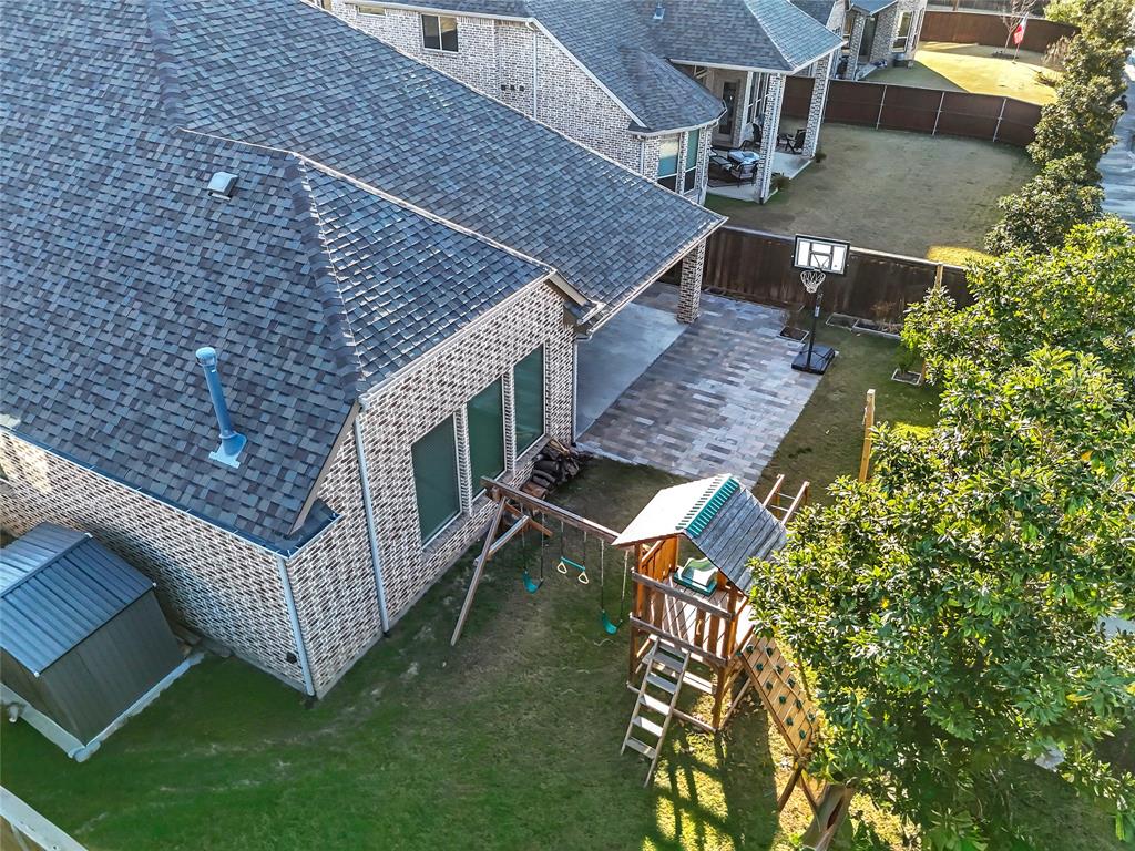 1011 Prairie Ridge Lane Arlington, TX 76005 - Photo 2 of 32 Expansive backyard featuring a covered patio with paver flooring, mature trees, and a storage shed
