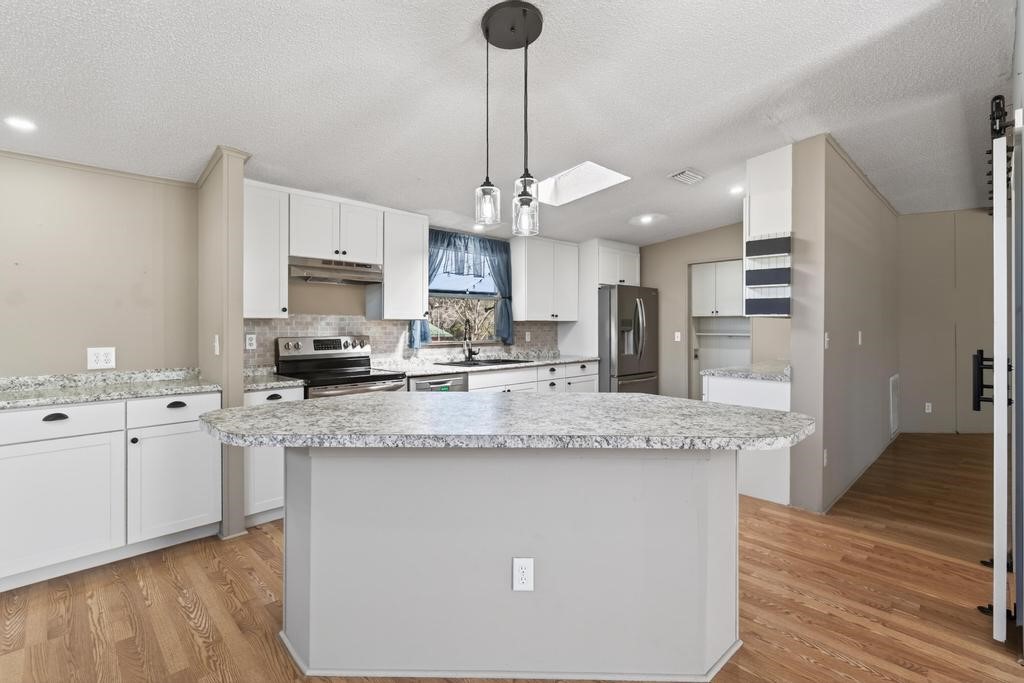 2744 Roy Sikes Road Hilliard, FL 32046 - Photo 22 of 97 a kitchen with stainless steel appliances granite countertop a sink a stove a refrigerator and island with wooden floor