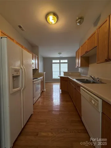 a kitchen with stainless steel appliances granite countertop a refrigerator a stove top oven a sink dishwasher and wooden cabinets with wooden floor