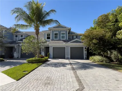 a front view of a house with a yard and palm trees