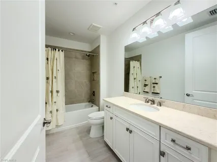 a bathroom with a double vanity sink toilet mirror and shower