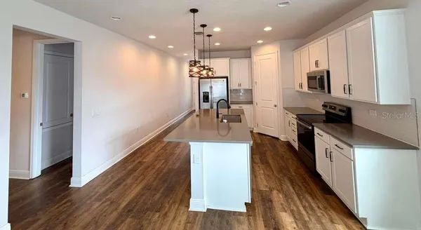 a kitchen with stainless steel appliances granite countertop wooden floors a refrigerator and a stove