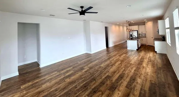 a view of a kitchen with refrigerator and wooden floor
