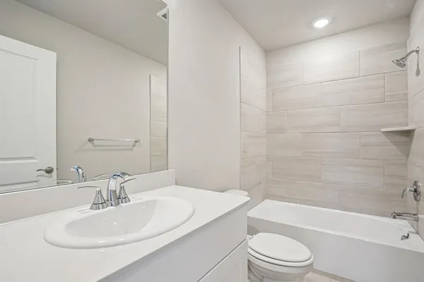 a bathroom with a bathtub shower sink vanity mirror and toilet
