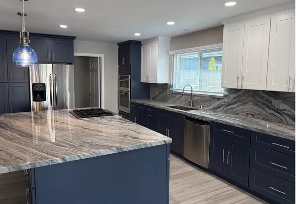 a kitchen with granite countertop kitchen island stainless steel appliances a sink stove and refrigerator