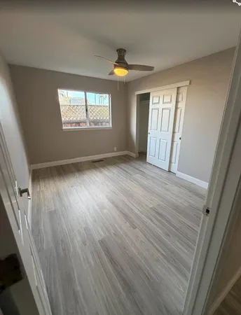 a view of an empty room with wooden floor and a window