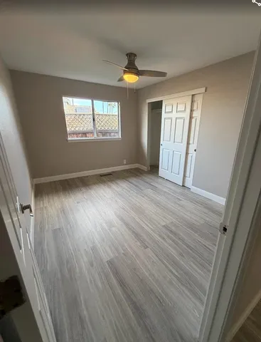 a view of an empty room with wooden floor and a window