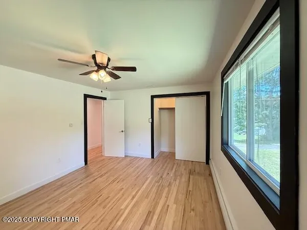 a view of empty room with wooden floor and fan