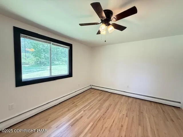 an empty room with wooden floor fan and windows