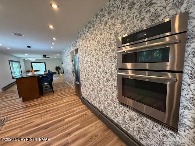 a kitchen with stainless steel appliances a stove a microwave and a hard wood floor
