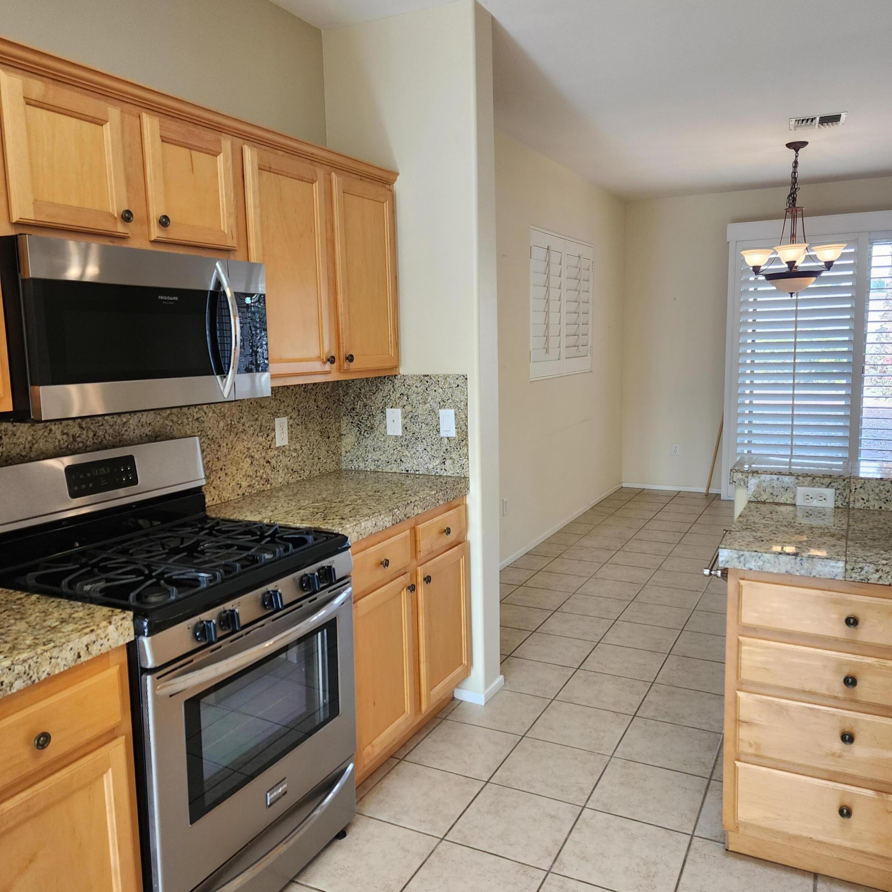 78786 Silver Lake Terrace Palm Desert, CA 92211 - Photo 9 of 20 a kitchen with granite countertop a stove a microwave and cabinets
