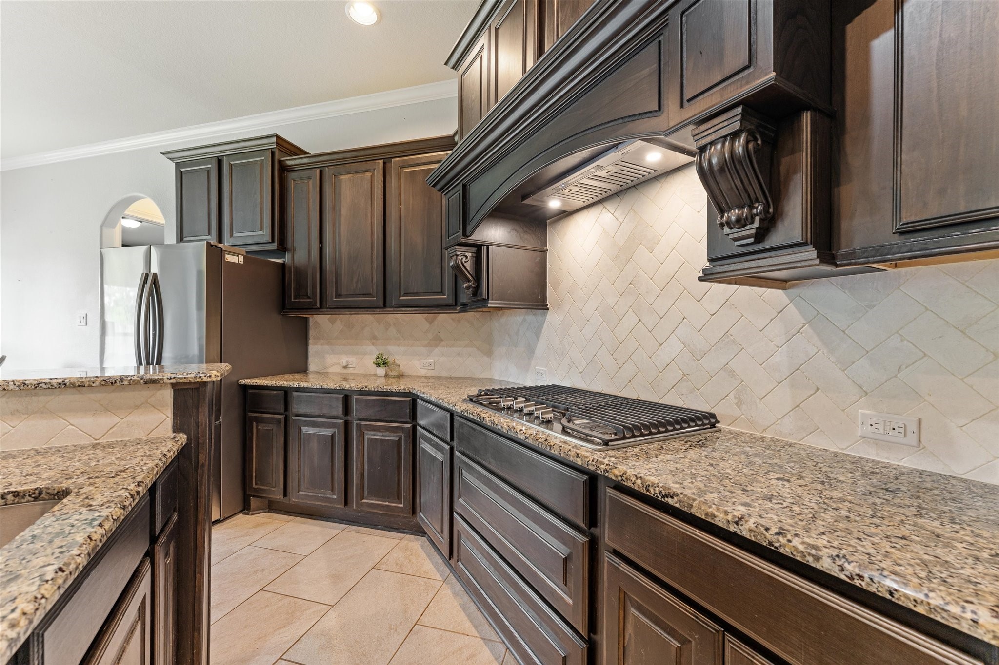 2506 Barclay Lake Lane Spring, TX 77388 - Photo 11 of 35 Cook in style with plenty of space to entertain. A gas cooktop, herringbone tile backsplash, and granite counters combine timeless craftsmanship with everyday convenience.
