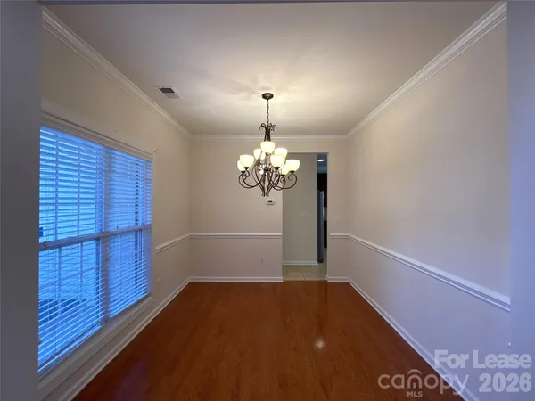 a view of a hallway with wooden floor and a chandelier
