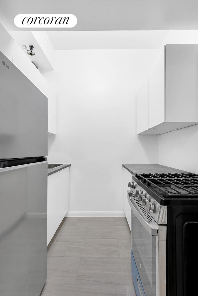 2830 Briggs Avenue, Unit WIA Bronx, NY 10458 - Photo 5 of 7 a kitchen with granite countertop cabinets and white appliances
