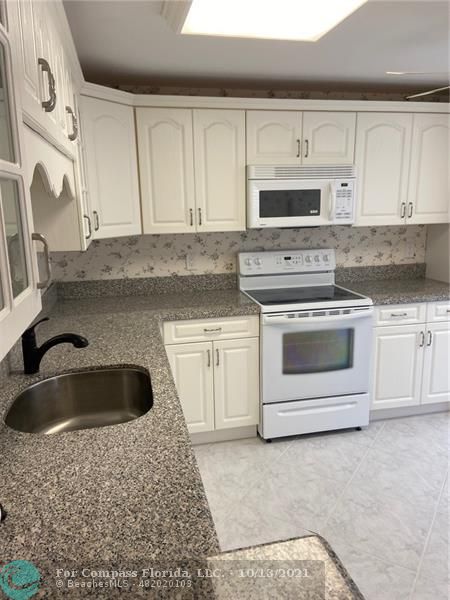 a kitchen with granite countertop white cabinets and white stainless steel appliances