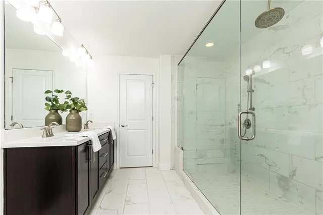 a bathroom with a shower sink vanity granite and mirror