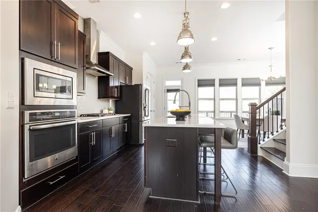 a kitchen with stainless steel appliances kitchen island granite countertop a stove a sink dishwasher and a refrigerator with wooden floor