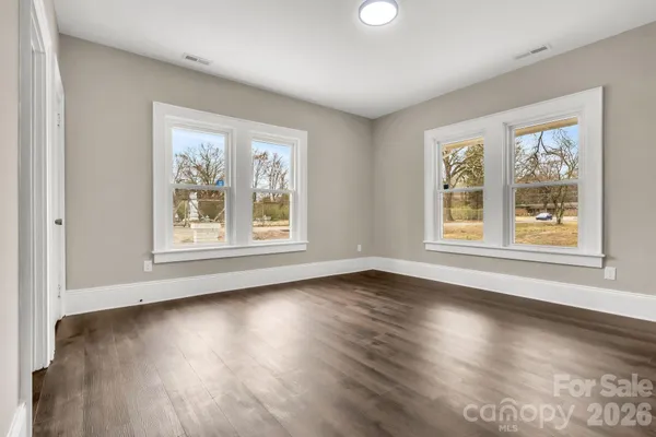 a view of an empty room with wooden floor and closet