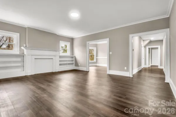 a view of an empty room with a kitchen and a window