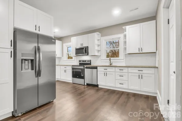 a kitchen with granite countertop white cabinets and stainless steel appliances