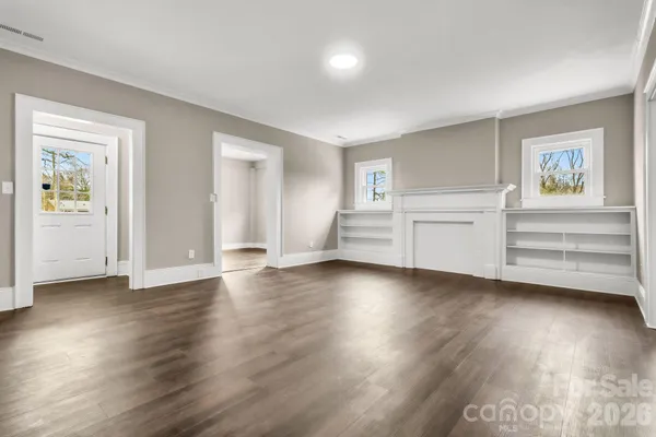 an empty room with wooden floor closet and windows