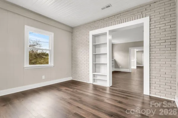 a view of an empty room with wooden floor and windows