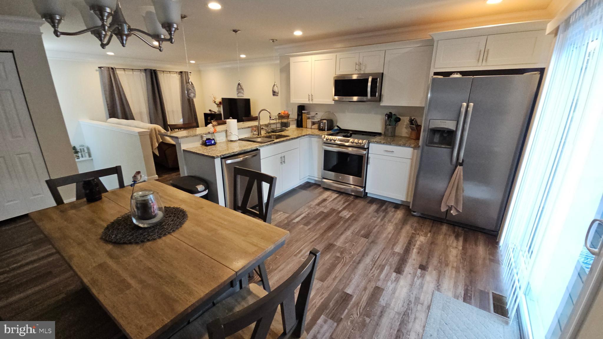 809 Duvall Highway Pasadena, MD 21122 - Photo 11 of 38 a kitchen with stainless steel appliances a dining table chairs refrigerator and microwave