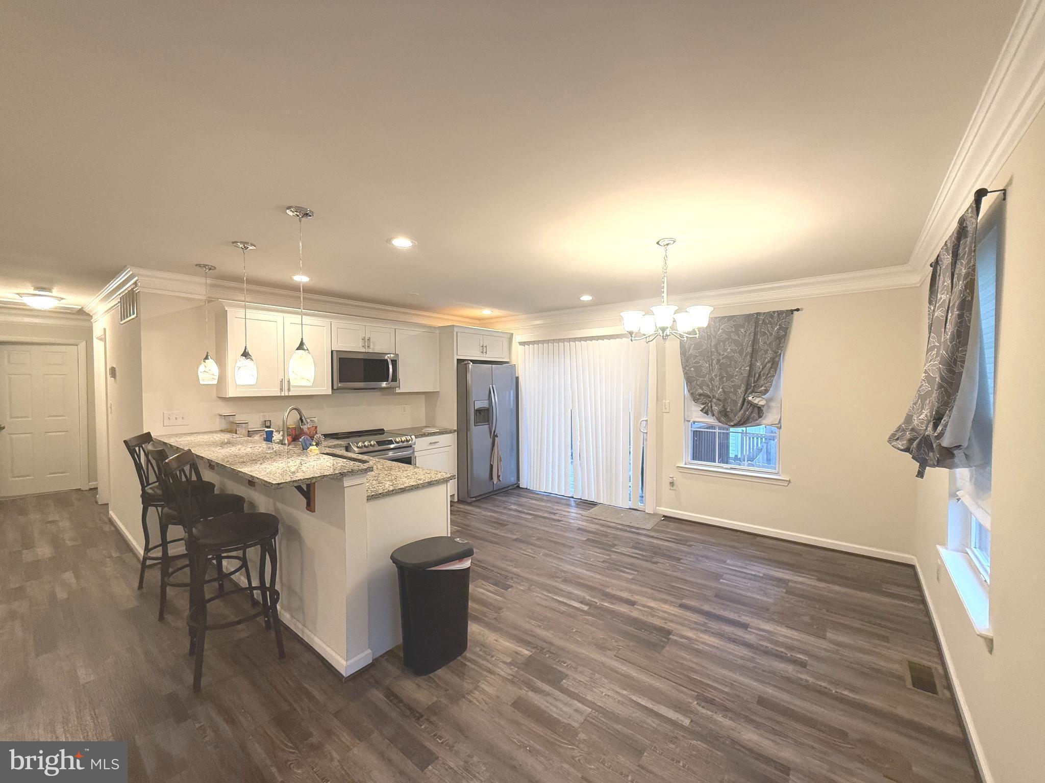 809 Duvall Highway Pasadena, MD 21122 - Photo 4 of 38 a kitchen with a stove a refrigerator and a dining table with wooden floor