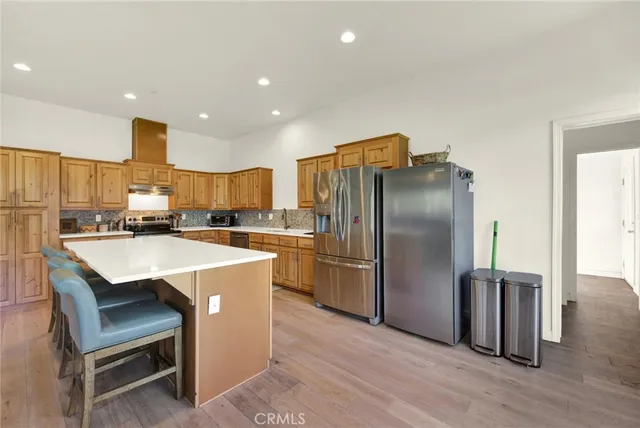 a view of a kitchen with kitchen island a large window cabinets a sink and stainless steel appliances