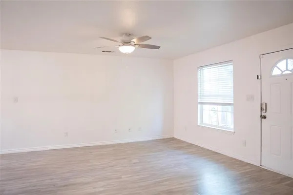 an empty room with wooden floor and windows