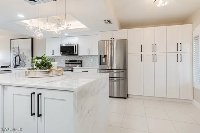 a kitchen with stainless steel appliances kitchen island granite countertop a refrigerator and a sink
