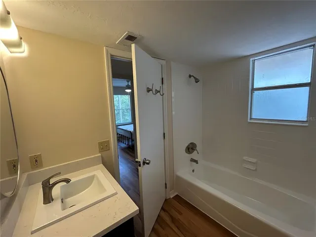 a bathroom with a tub sink vanity and a shower