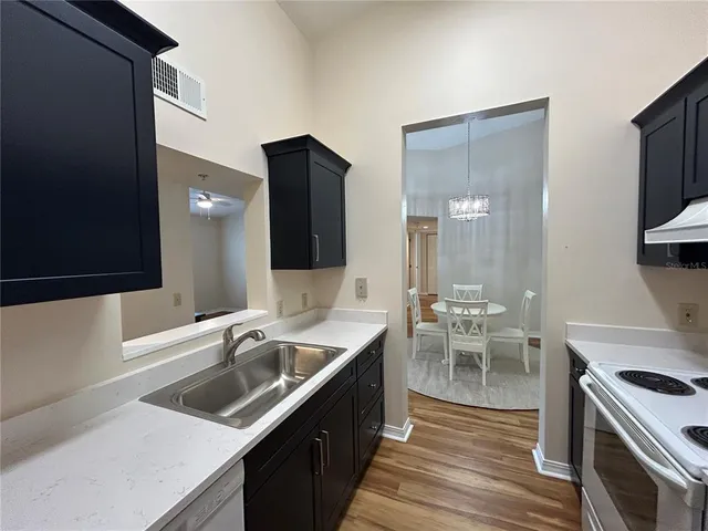 a kitchen with a sink stove and wooden floor